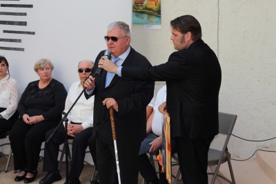 Predstavnika Zveze društev slepih in slabovidnih Slovenije med nagovorom; eden govori v mikrofon in drži belo palico.